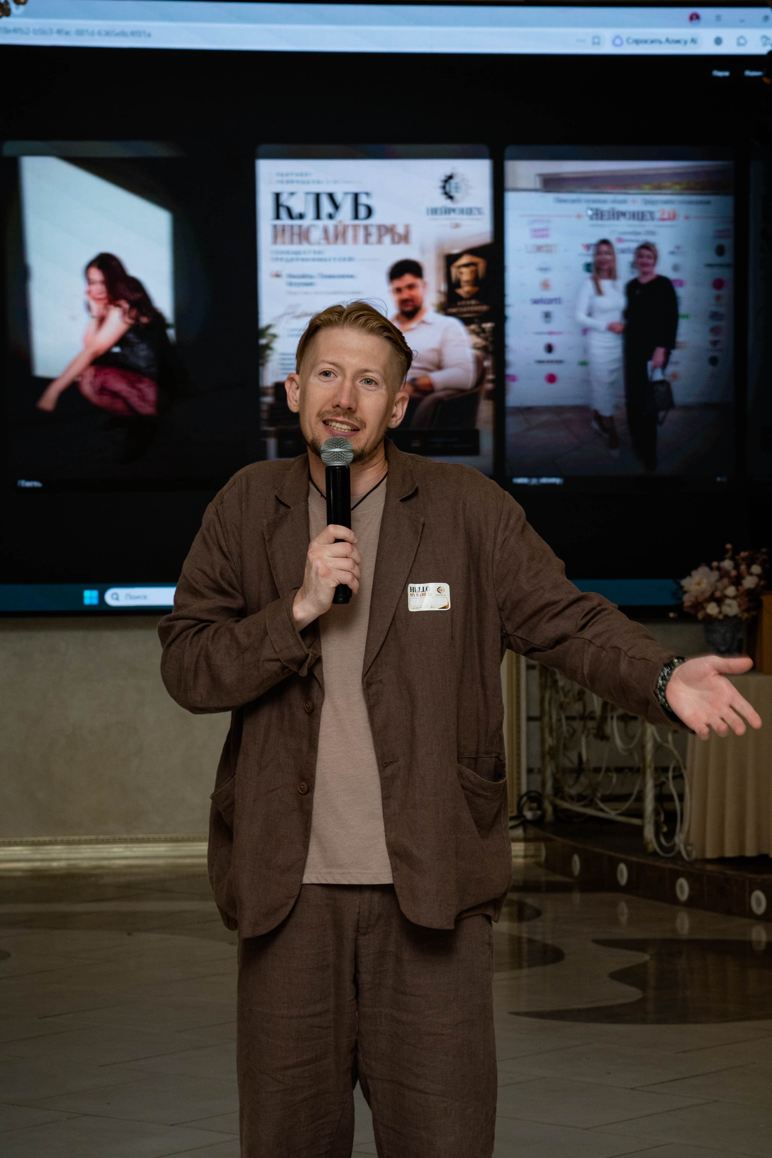 Host speaking in front of the photo wall